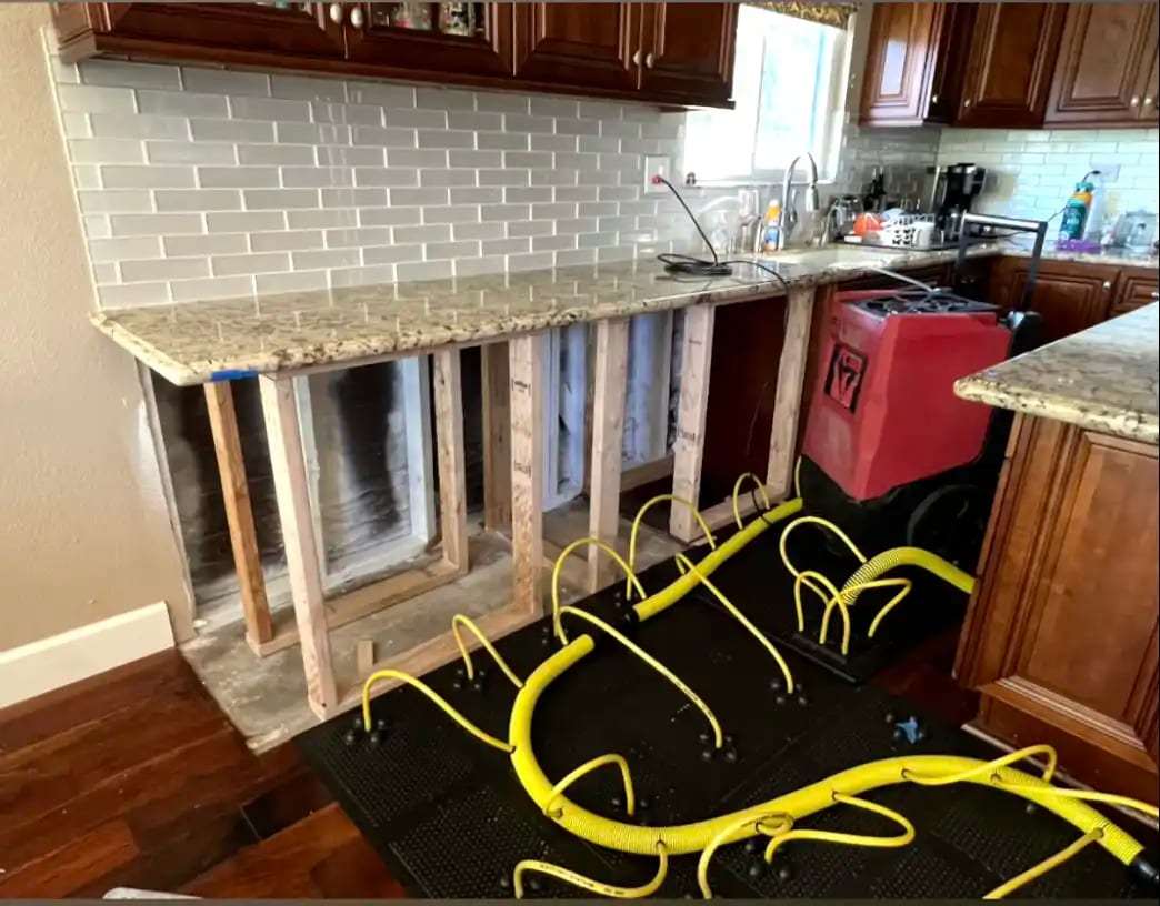 Kitchen with the lower cabinets removed and drying mats under the counter
